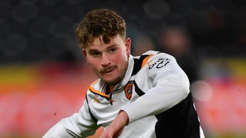 Hugh Parker warming up for a Hull City game wearing a white Hull drill top