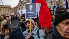 Протестующие в зимней одежде с флагами Чехии, женщина держит плакат с портретом Петра Павела.