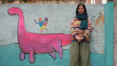 Kim Duc a Vietnamese architect leans against a wall with a mural painted on it.