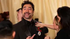 الممثل الإسباني خافيير بارديم يرتدي دبوساً كتب عليه "فلسطين" وشعاراً مناهضاً للحرب على السجادة الحمراء خلال وصول الضيوف إلى حفل توزيع جوائز الأوسكار في دورته الـ98 في هوليوود، لوس أنجلوس، الولايات المتحدة، 15 مارس/آذار 2026 