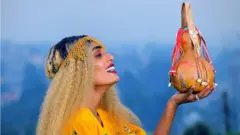 በጨሌ የተዋበ ቅል የያዘች ሴት