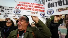 "Çocuklarımızın mezarı üstünden 27. Madde geçemez" yazılı döviz taşıyan bir kadın