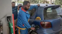 ቪትዝ መኪና ላይ ነዳጅ የሚቀዳ የነዳጅ ማደያ ሠራተኛ 