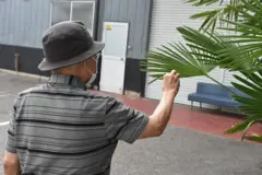 Idoso de costas, mexendo em planta