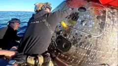 Hombre a punto de abrir la escotilla de la nave que amerizó