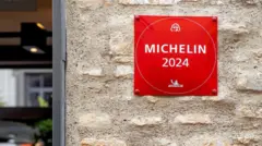 A foto mostra uma parede com uma placa vermelha escrito em branco "Michelin 2024".