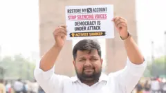 Sandeep Singh, an X user, holds up a placard saying 'Restore my X account. Stop silencing voices. Democracy under attack' on a street in India