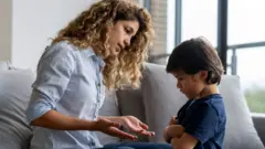 Kollarını kavuşturmuş ve başını öne eğmiş küçük erkek çocuğu, annesiyle müzakere yapmayı reddediyor.
