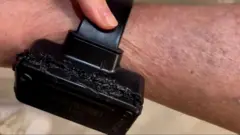 Imagem de uma tornozeleira eletrônica preta com sinais de derretimento. 