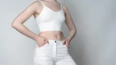 Beyaz bir pantolonda ellerini cebine sokan bir kadın