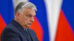 Виктор Орбан с угрюмым лицом на фоне российских триколоров 