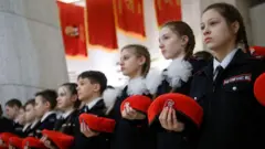Adolescentes russos com bonés vermelhos participam de cerimônia de ingresso em um movimento patriótico de cadetes do Exército da Juventude