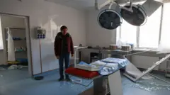 Lekarz stoi wewnątrz szpitala położniczego w Odessie, na podłodze leży rozbite szkło