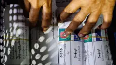 ဇန်နဝါရီလ ၂၅ ရက်တုန်းက ပြုလုပ်ခဲ့တဲ့ စစ်တပ်ရွေးကောက်ပွဲ နောက်ဆုံးအကျော့မှာ မန္တလေးမြို့က မဲရုံတစ်ရုံမှာ ရေတွက်ပြီးမဲတွေနဲ့အတူ တွေ့ရတဲ့ကြိုတင်မဲစာရွက်တွေဖြစ်ပါတယ်။ စာရွက်တစ်ခုပေါ်မှာဆိုရင် ကြံ့ခိုင်ရေးပါတီက ကိုယ်စားလှယ် ဦးကိုကိုဦးနဲ့ ပြည်သူ့ရှေ့ဆောင်ပါတီက ကိုယ်စားလှယ် ဦးစန်းလွင်တို့ရဲ့နာမည်တွေကို မြင်တွေ့ရပါတယ်။ လက်နှစ်ဖက်ရဲ့ လက်ချောင်းတွေက အဲဒီမဲစာရွက်တွေပေါ်မှာ မြင်တွေ့ရ 