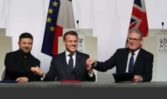 Zelenskiy, Macron ve Starmer oturdukları kürsüde el sıkışıyor ve hallerinden çok memnun görünüyorlar.