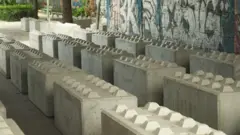 Large concrete blocks with spikes on a walkway under a bridge