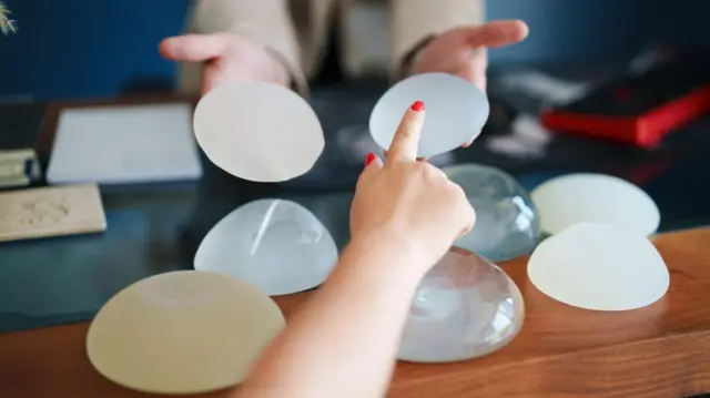 ရင်သားအစားထိုး ကုသမှု ခံယူရာမှာ သုံးတဲ့ ဆီလီကွန်တွေကို လက်ညှိုးထိုးပြနေတဲ့ အမျိုးသမီးတစ်ဦးရဲ့ လက်နဲ့ တစ်ဖက်မှာ စီလီကွန်နှစ်ခုကို လက်ပေါ် တင်ပြီး ချိန်ထိုးပြနေတဲ့ အမျိုးသမီးတစ်ဦးရဲ့ လက်တစ်စုံကို မြင်ရတာဖြစ်ပါတယ်။ 