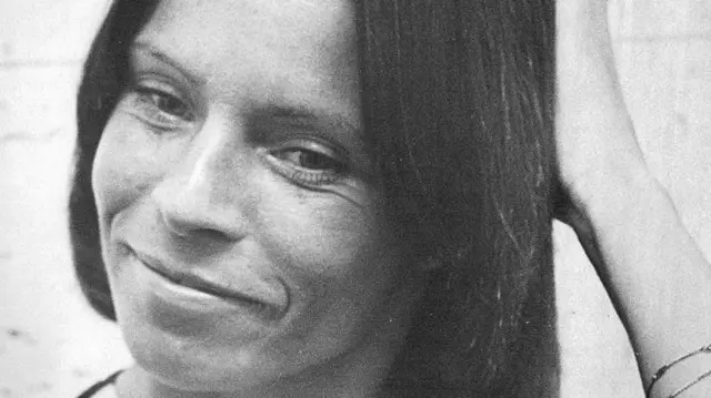 Una imagen en primer plano, en blanco y negro, de Kitty O'Neil sonriendo y apartando la mirada de la cámara.