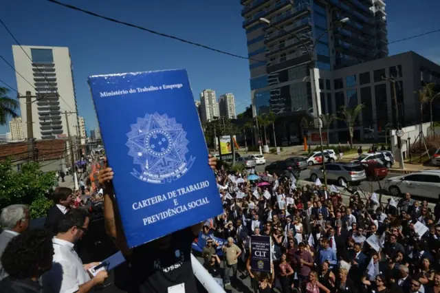 Manifestantes seguram uma carteira de trabalho gigante durante protesto em São Paulo
