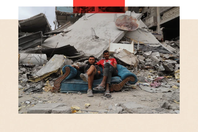 Deux hommes assis sur un autocar au milieu des décombres.