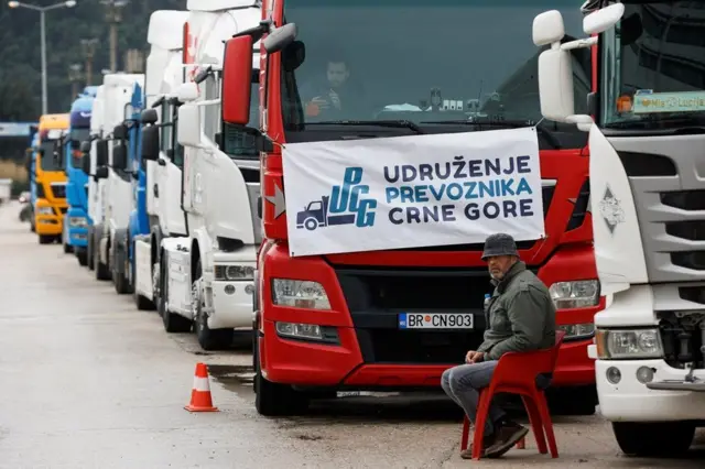камионџије, црногорски камиони, црногорске камионџије, возач камиона седи поред десетине возила паркираних испред Луке Бар