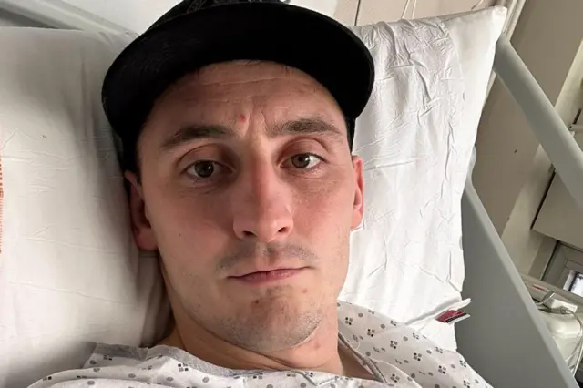 Sam Davies lying on a hospital bed 