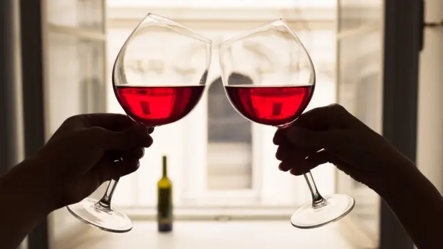 Two people's hands toasting with red wine ලිංගික ,මත්පැන් ,මධ්යසාර