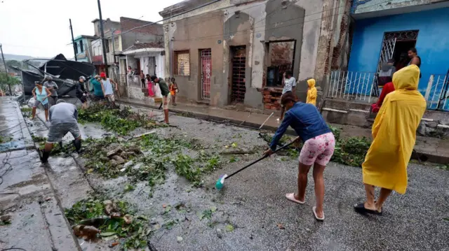Nekoliko ljudi čisti ulice i rasklanja polomljeno granje posle uragana na Kubi