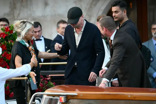 Леонардо ди Каприо в черном костюме и с бейсболкой, которая скрывает его лицо.