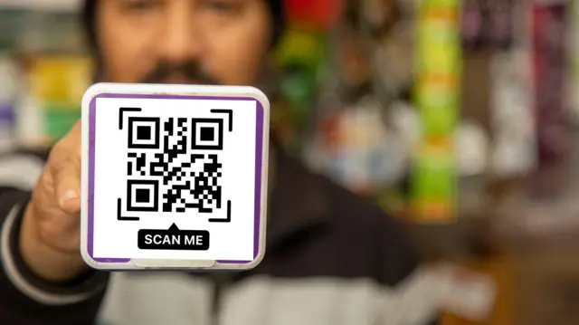 Person Holding QR Code Payment Card for Digital Transaction in Indian Village Store