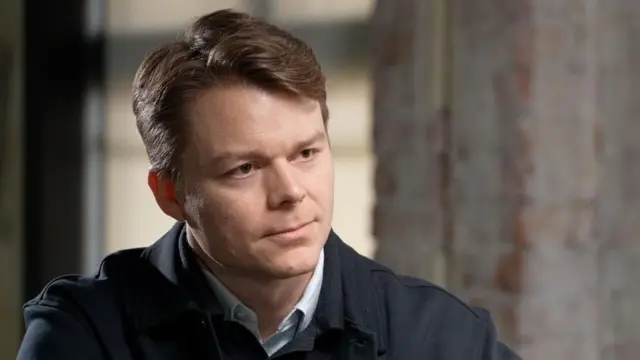 Palantir yöneticisi Mosley lacivert bir üst, mavi bir gömlekle görünüyor.