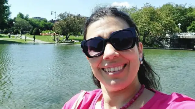 Güneşli bir günde bir gölün önünde fotoğraf çektiren güneş gözlüklü Pekky Marquez.