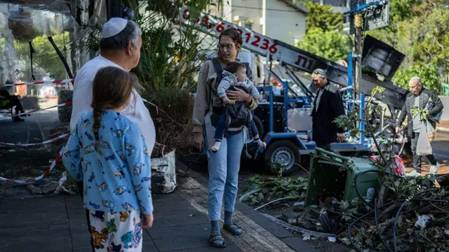 28 Mart 2026’da Ramat Gan’da İran’a ait bir füzenin parçalarının gece boyunca isabet ettiği bir bölgede, bölge sakinleri hasarı inceliyor