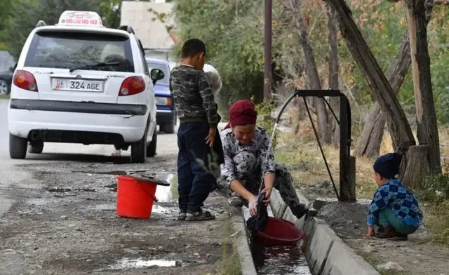 Аёл ариқда кир ювяпти, ўнг томонида бир ўгли тик туриб қараяпти, иккинчи томонида иккичи ўгли қараб тизза чўкиб ўтирибди