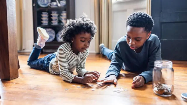 A boy and a girl counting change on floor at home