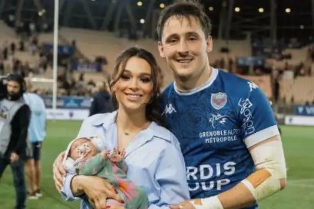 Sam Davies in rugby kit with his wife and baby 