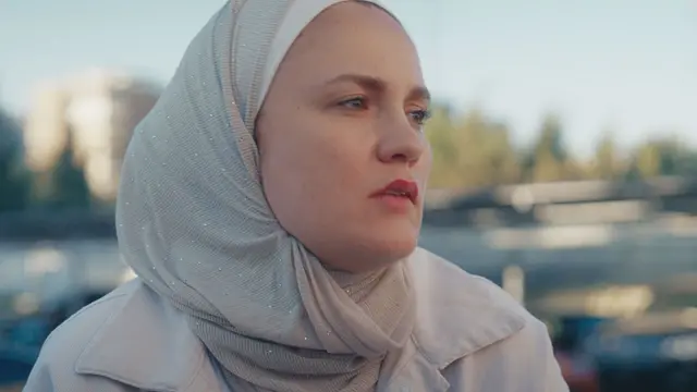 ریم در حالی که روسری خاکستری به سر دارد و به افق خیره شده است.