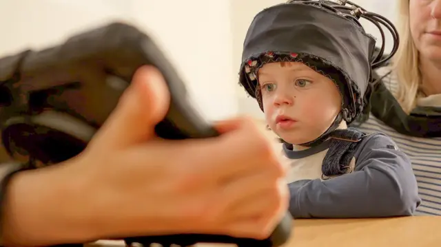 Yosh bola - taxminan ikki yoshli go'dak - iPadga tikilib o'tiradi, aftidan ekrandagi narsalarga berilib ketgan. iPadni ko'rish imkonidan mahrum bo'lgan psixologiya tadqiqotchisi ushlab turibdi va bola onasining tizzasida o'tirib, oldidagi ekrandagi narsalarni tomosha qilmoqda.