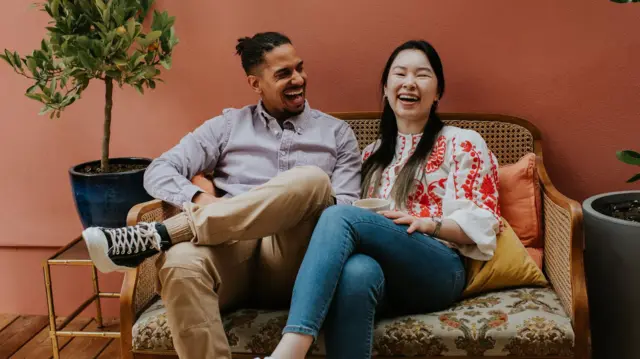 Yan-yana oturmuş kişi və qadın gülürlər