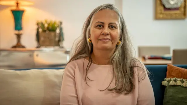 A médica neonatologista Lilia Embiruçu sentada em um sofá. 