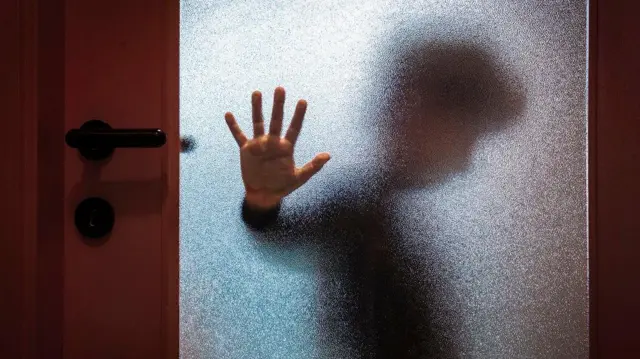 Ilustrasi seorang anak laki-laki berdiri di balik pintu.