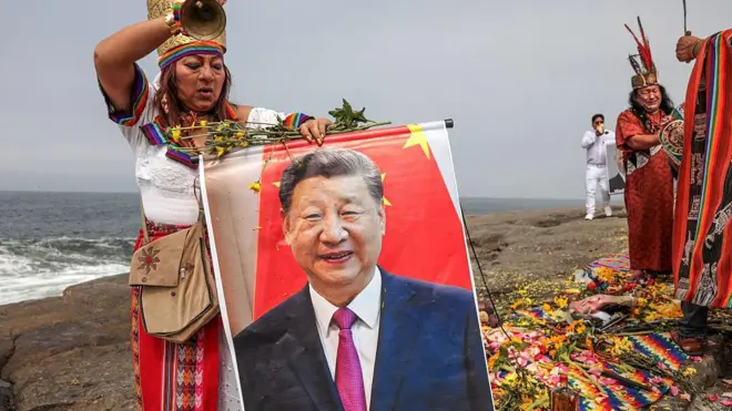 Una curandera vestida con ropas folklóricas sujeta un retrato del presidente de China, Xi Jinping, durante un ritual tradicional en Chorrillos, Lima.