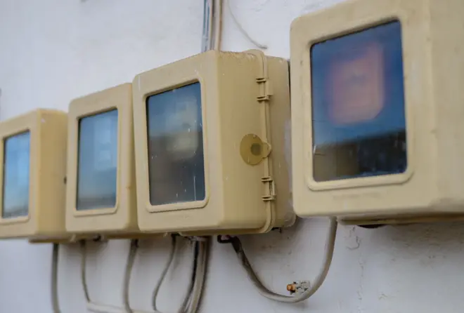 Four analog electricity meters in a row on the outside of a building close up shot.