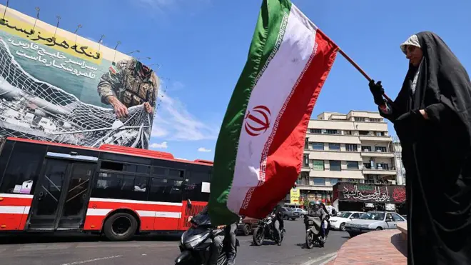 一名女子在巨幅看板前揮舞伊朗國旗。