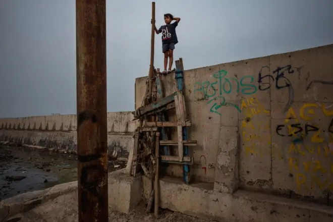 پسری روی دیوار جدیدی که برای محافظت از جاکارتا در برابر بالا رفتن سطح دریا ساخته‌ شده است، راه می‌رود