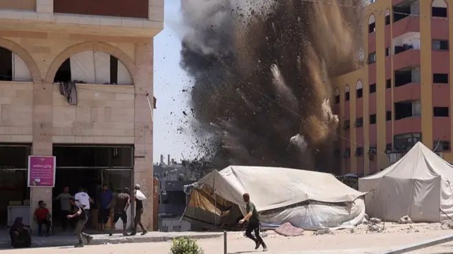 Palestinians rush for cover as smoke billows after an Israeli strike on a building in Jabalia in the northern Gaza Strip