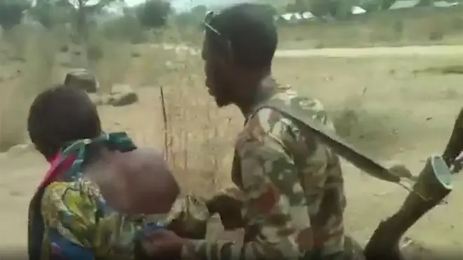 Un soldado empuja a una mujer