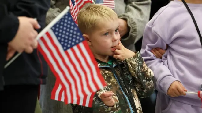 Des membres du premier groupe de Sud-Africains blancs ayant obtenu le statut de réfugié pour avoir été considérés comme victimes de discrimination raciale dans le cadre du plan pour les réfugiés du président américain Trump, tiennent des drapeaux américains alors qu'ils participent à un événement de rencontre et d'accueil, à l'aéroport international de Dulles, à Dulles, en Virginie, aux États-Unis.