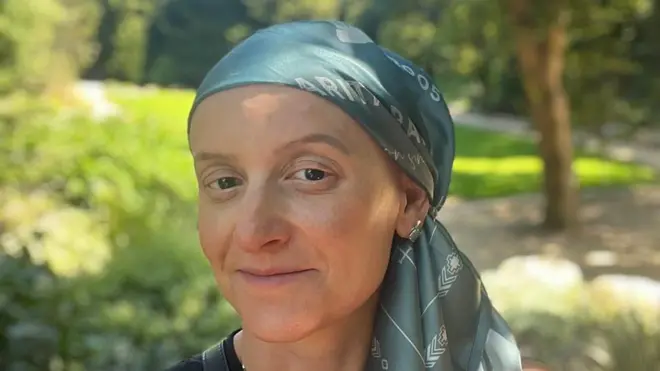 Luisa Toscano podczas leczenia, ma na głowie zieloną chustę. Spogląda spokojnie w obiektyw aparatu.