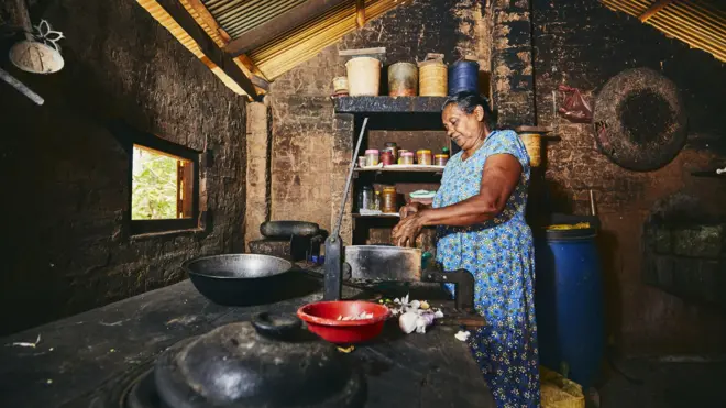 Rural woman preparing food in traditional home kitchen. Domestic life in Sri Lanka.